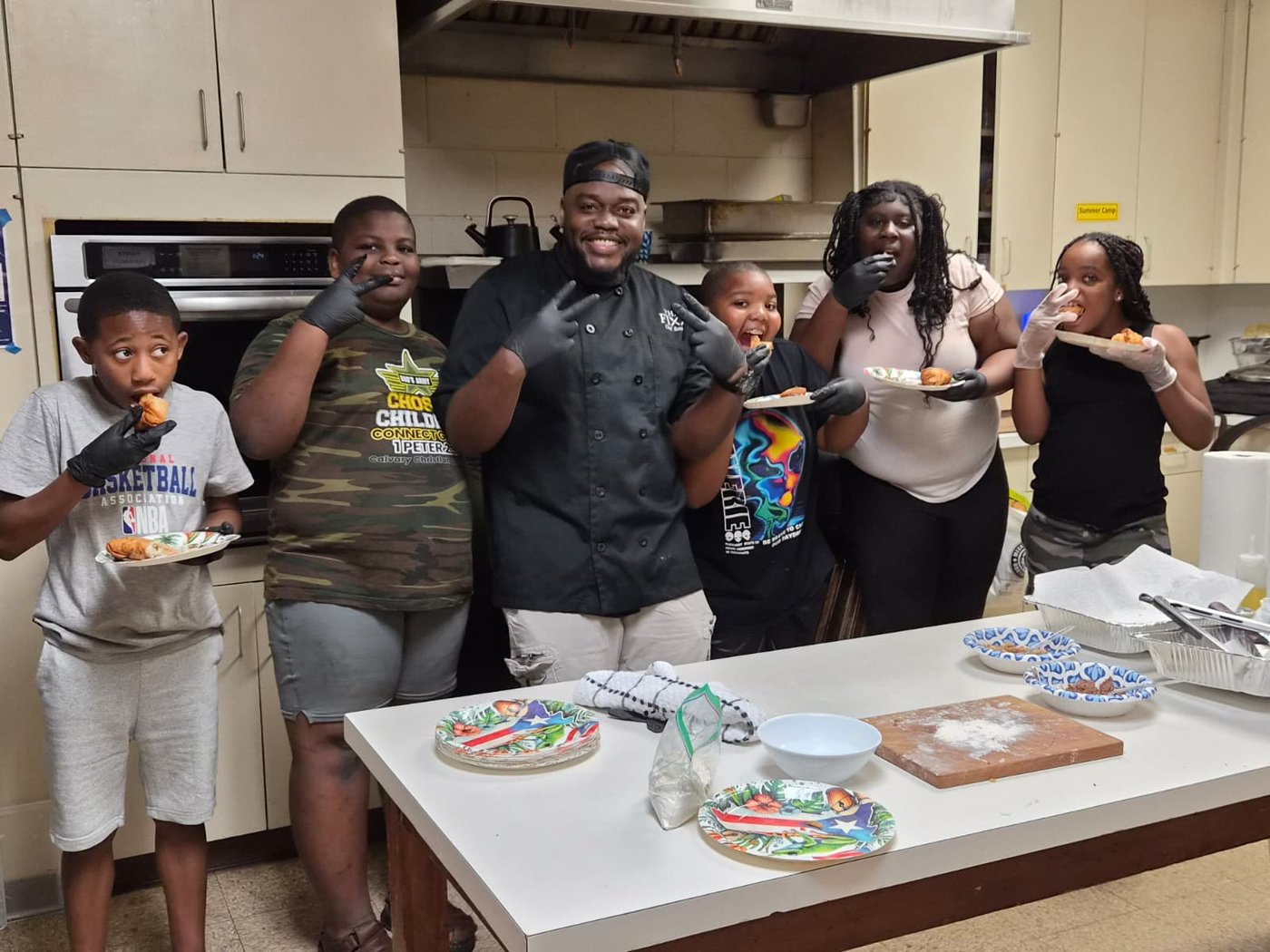 Chef Kareem Pearson and kids tasting the food they made together in a free cooking class